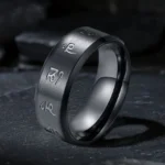 Black Jambhala mantra titanium steel ring with hand-engraved sacred mantras, three-quarter view showing matte black finish and polished inner edge