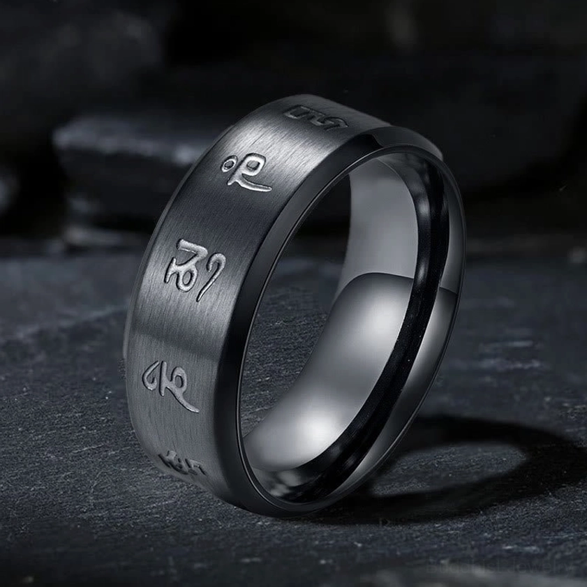 Black Jambhala mantra titanium steel ring with hand-engraved sacred mantras, three-quarter view showing matte black finish and polished inner edge