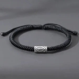 Black koi fish bracelet overhead flat lay showing adjustable sliding knot and silver fish charm on grey background