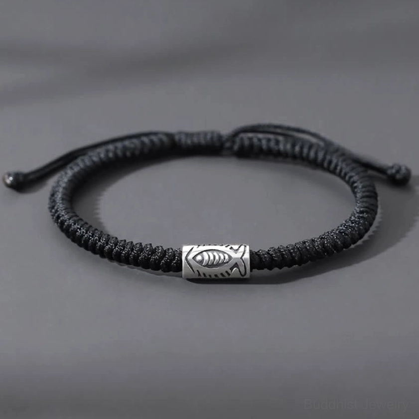 Black koi fish bracelet overhead flat lay showing adjustable sliding knot and silver fish charm on grey background