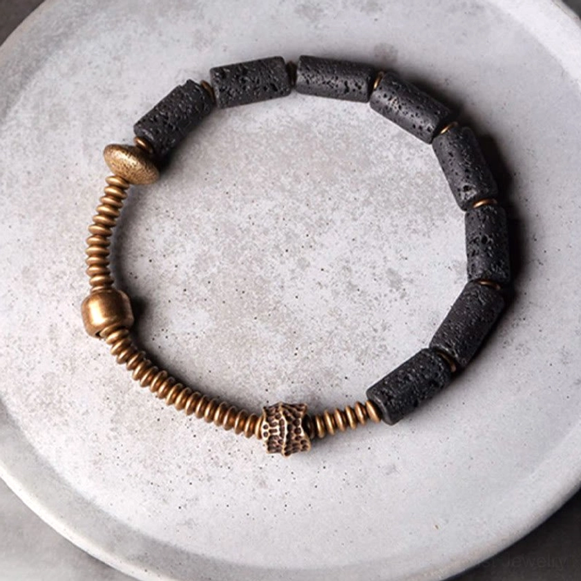 Full circular black lava rock and copper bracelet on light gray display plate