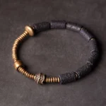 Black lava rock and copper beaded bracelet top-down flat lay showing cylindrical lava beads with hammered copper accent