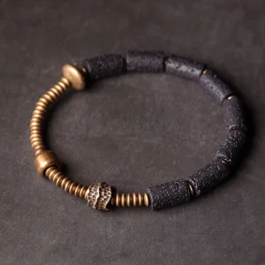 Black lava rock and copper beaded bracelet top-down flat lay showing cylindrical lava beads with hammered copper accent