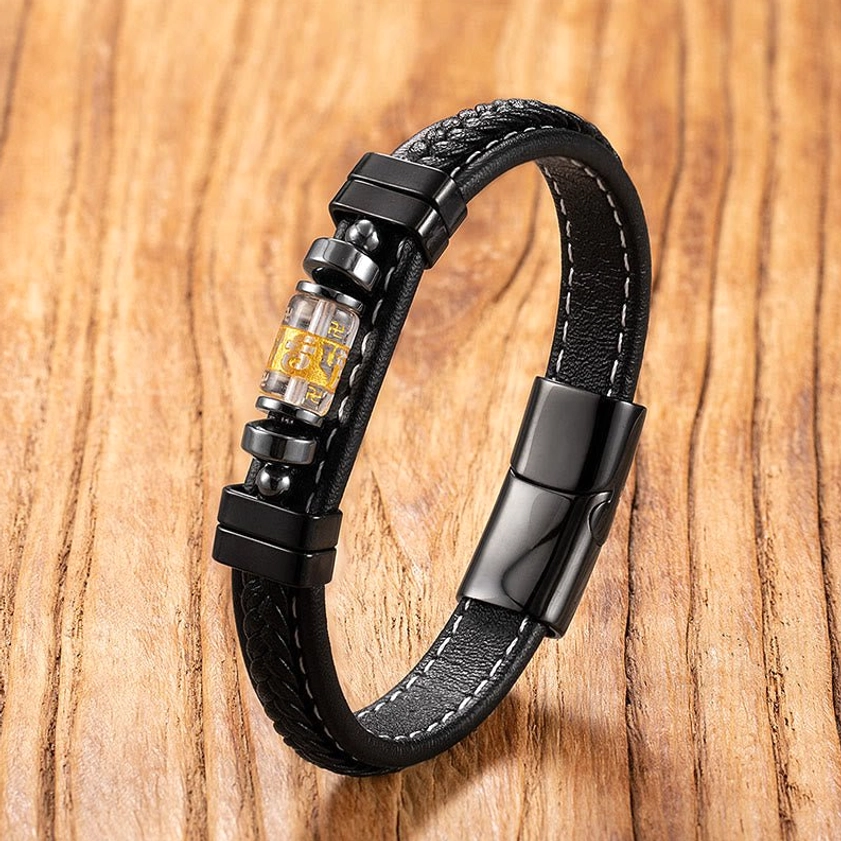 Black leather mantra bracelet with transparent-cased engraved bead and titanium steel clasp, side overhead view on wood