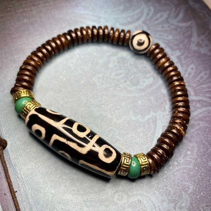 black nine-eye dzi bead bracelet with white eye markings, coconut shell spacers, and turquoise gemstone accents in traditional Buddhist design