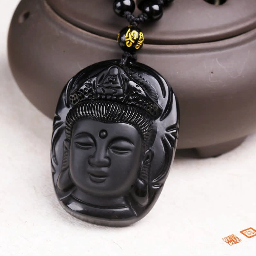Black obsidian Kwan Yin pendant showcasing smooth matte finish, detailed facial carving, and mantra spacer bead, front flat view