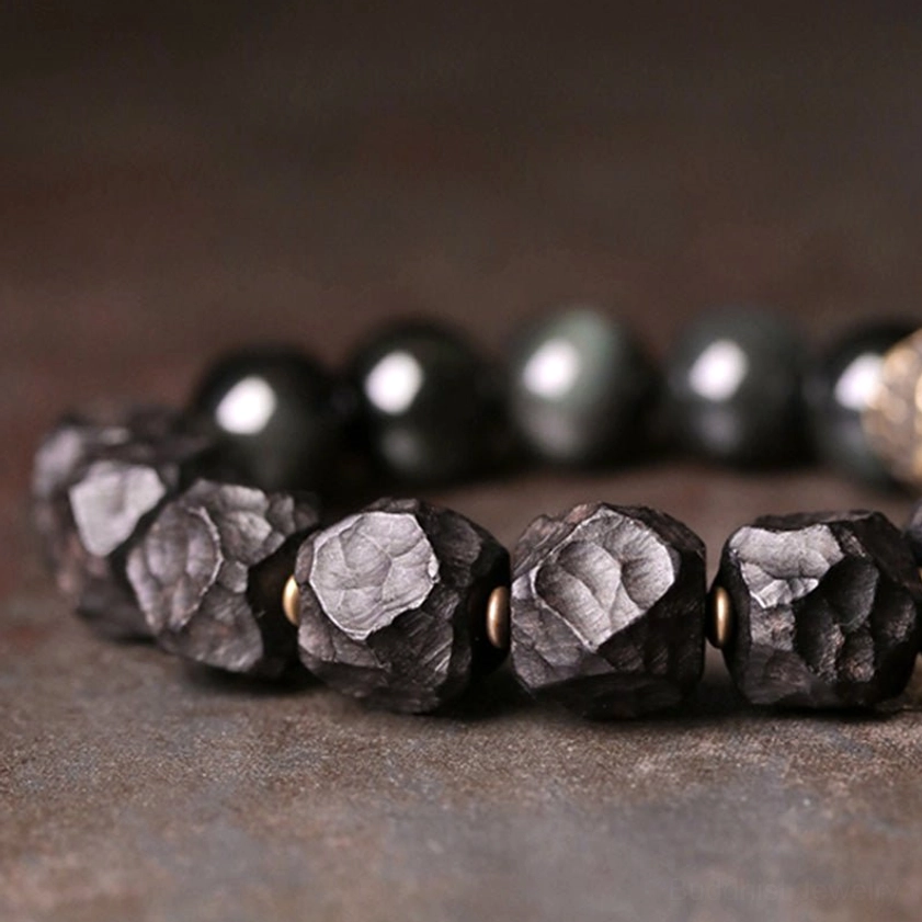Cat-eye black obsidian beads and carved ebony wood beads - macro close-up showing glossy polished obsidian texture
