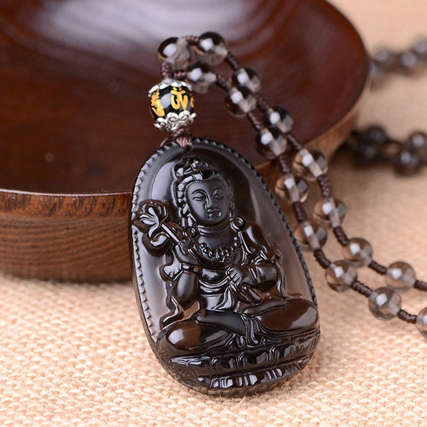 Glossy black obsidian carved seated Bodhisattva pendant with beaded chain, right-top perspective on linen fabric