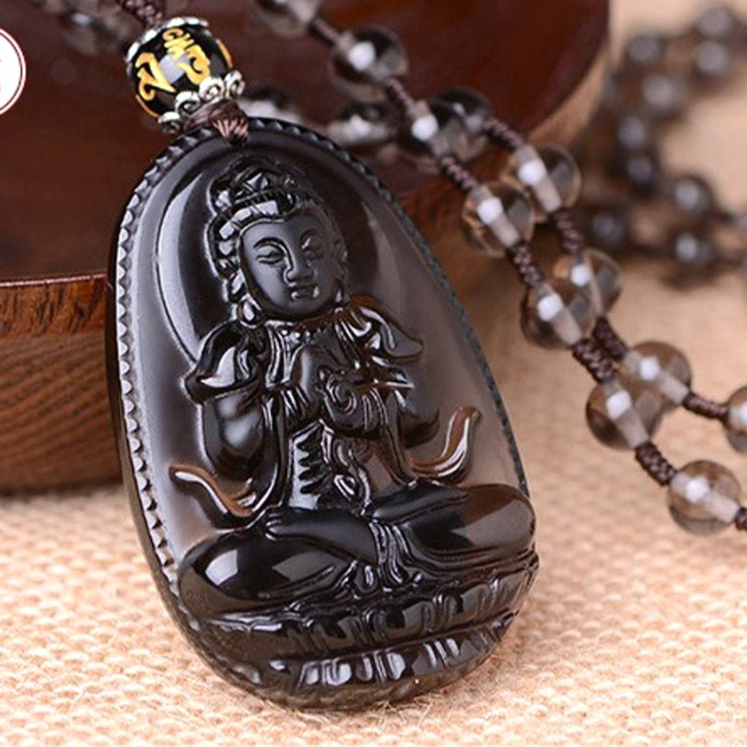 Black obsidian carved Buddha pendant necklace with beaded chain, left-top angled view on linen fabric and wooden tray