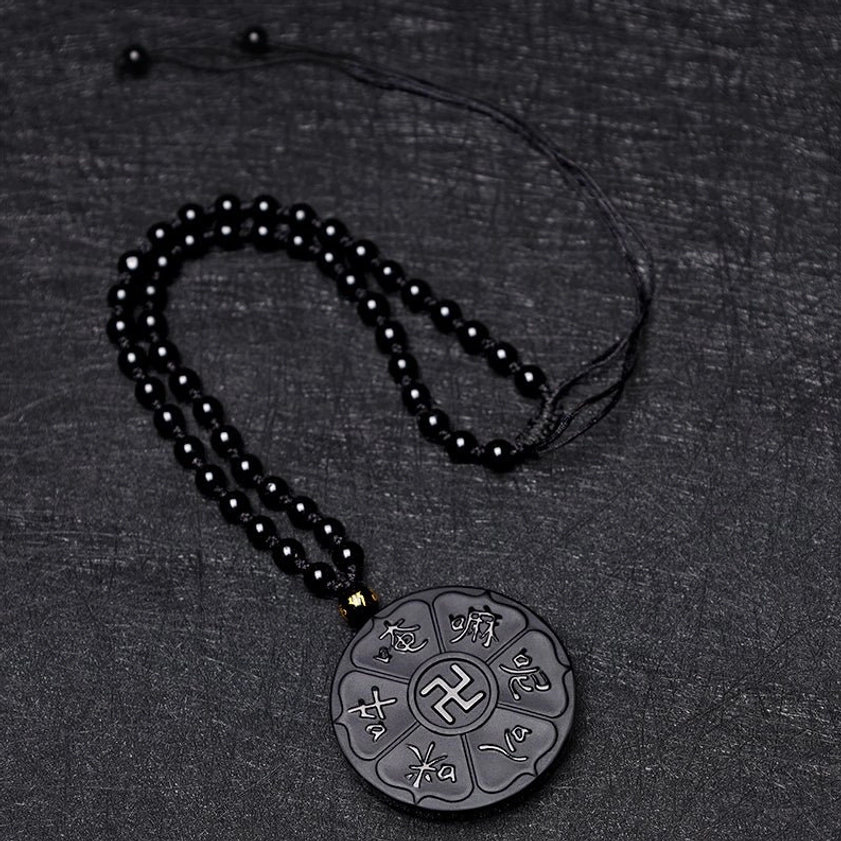 Top-down view of black obsidian beaded necklace chain with branded spacer on dark fabric