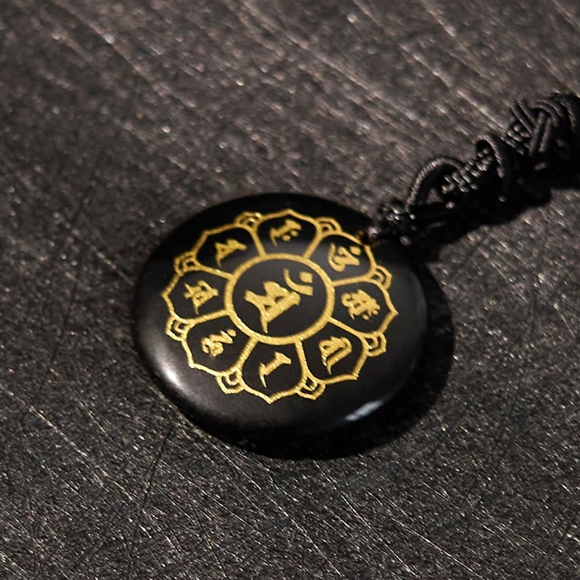 Black Obsidian Buddhist pendant showing Om Mani Padme Hum mantra with gold Sanskrit design, side detail view