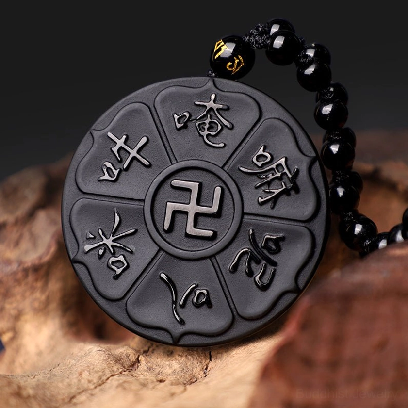 Side view of carved black obsidian Buddhist necklace pendant showing intricate mantra details