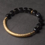 Black Obsidian and copper couple bracelet flat lay featuring hammered gold metal bar and polished black cube beads