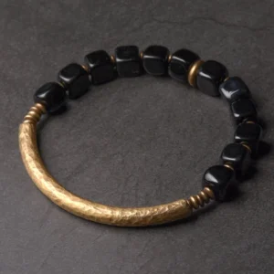Black Obsidian and copper couple bracelet flat lay featuring hammered gold metal bar and polished black cube beads