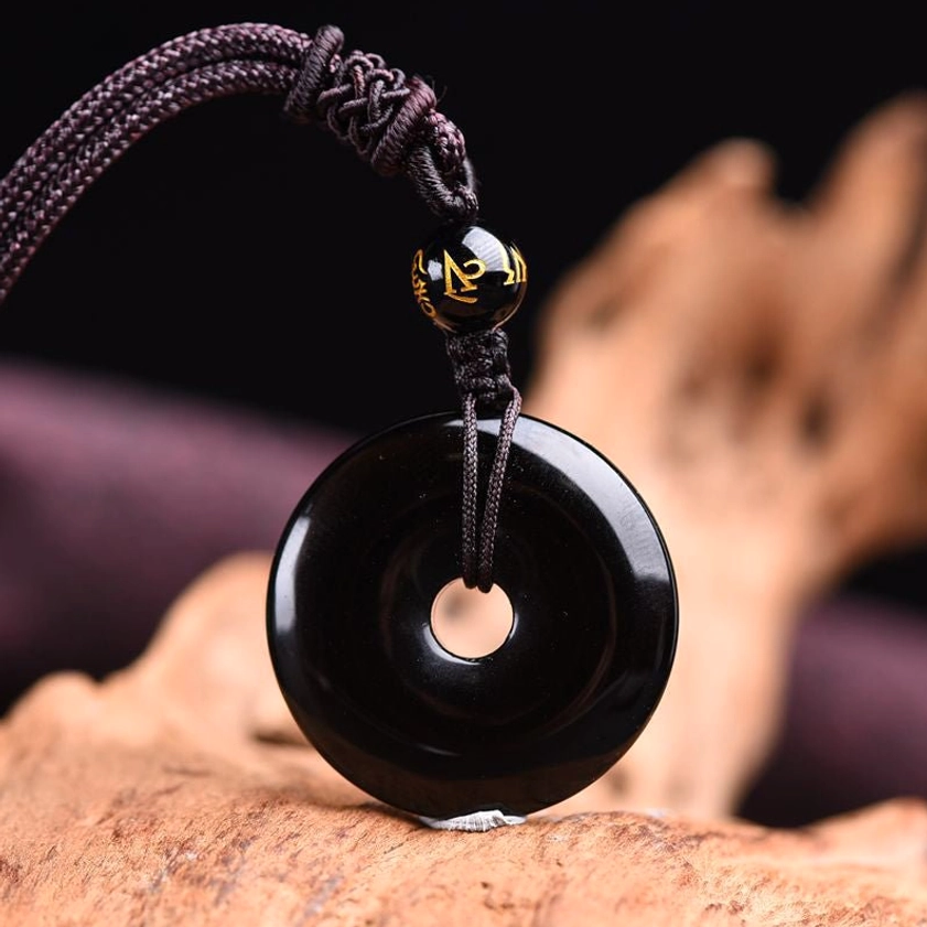 Solid black obsidian donut pendant on braided cord with Tibetan script accent bead