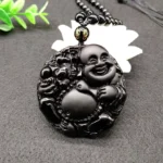 Black Obsidian Laughing Buddha pendant necklace with carved Maitreya design, close-up detail view showing intricate relief carvings and matte black finish