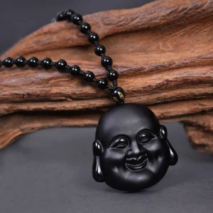 Black obsidian laughing Buddha pendant necklace with beaded chain and gold spacer bead, front view on wooden surface