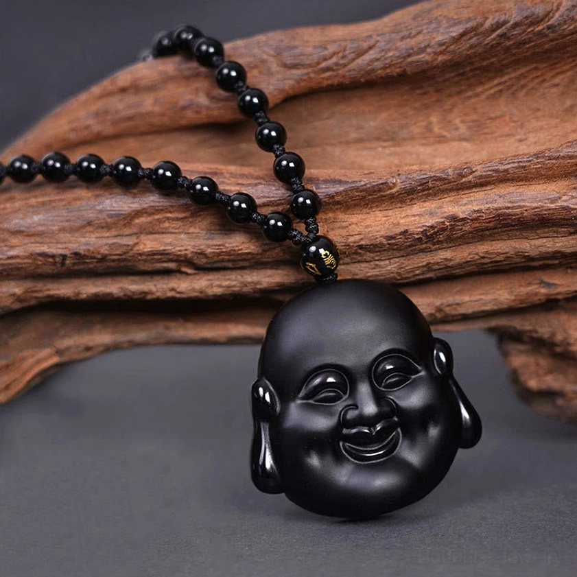 Black obsidian laughing Buddha pendant necklace with beaded chain and gold spacer bead, front view on wooden surface