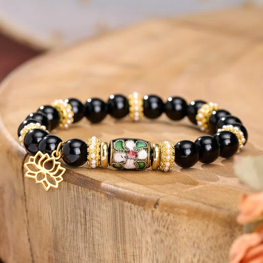 Close-up of black obsidian beads with cloisonné enamel lotus charm and gold spacers