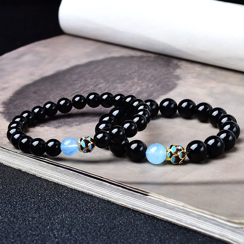 Two matching black obsidian lotus bracelets with identical design and metal spacer details