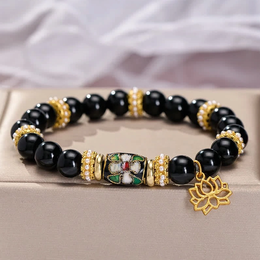 Side view of black obsidian lotus bracelet showing gold crystal spacers and enamel charm