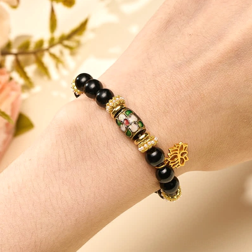 Black obsidian lotus bracelet worn on wrist with gold lotus dangle charm
