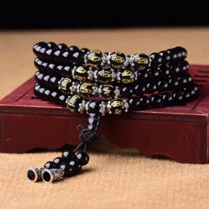Black Obsidian Om Mani Padme Hum Mala Bracelet with 108 beads, golden engraved script beads, and silver metal accents displayed on red wooden stand