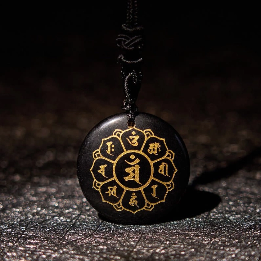 Black Obsidian Om Mani Padme Hum Buddhist necklace pendant with gold Sanskrit engraving and black braided cord, front close-up view