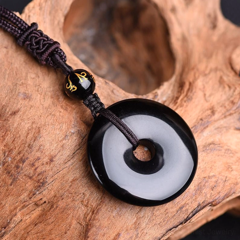 Polished black obsidian ring pendant necklace three-quarter view wooden background