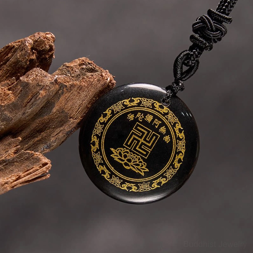 Black obsidian Buddhist necklace pendant oblique angle with braided cord on wooden and leather surface