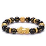 Black obsidian Buddhist bracelet with engraved Om Mani Padme Hum mantra beads and gold PiXiu charm, top-down flat lay view