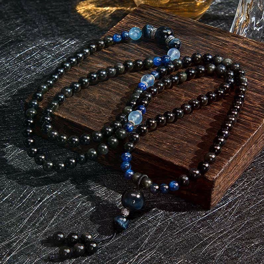 Overhead angled view of black obsidian prayer mala showing intricate bead work and decorative tassel pendant