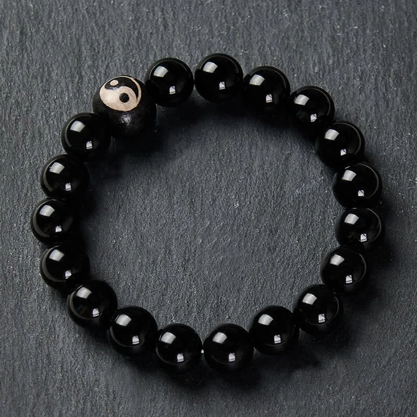 Black obsidian protection bracelet yin yang symbol centerpiece on gray matte background
