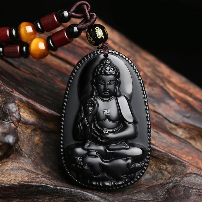Black obsidian zodiac guardian Buddha pendant necklace - direct front view with intricate Buddha carving on dark wooden background