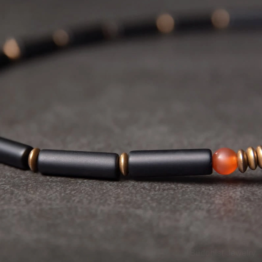 Black onyx tube beads with copper spacers and red agate accent showing bracelet strand construction detail