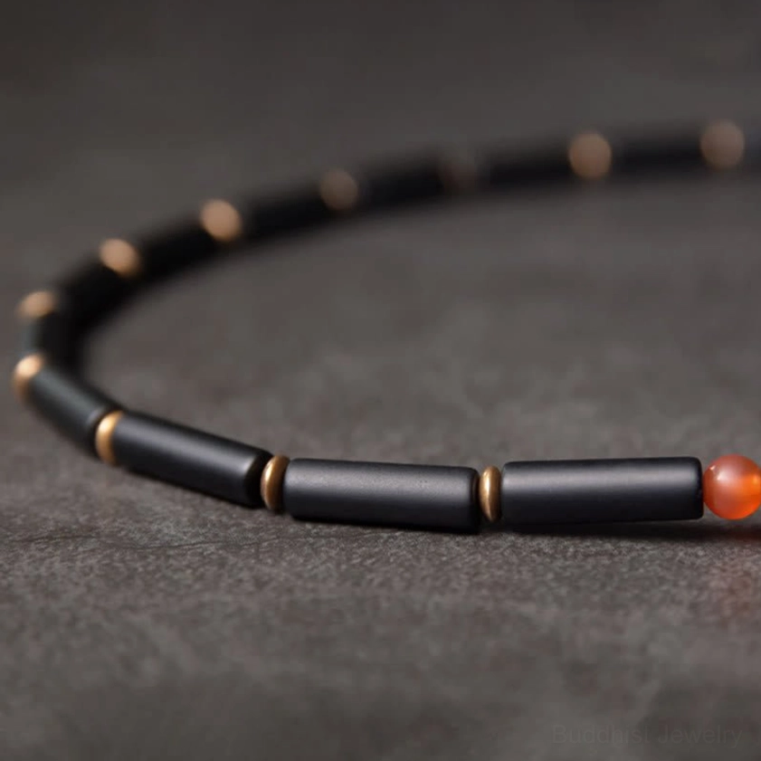Close-up detail of black onyx tube beads with copper spacers and red agate accent bead on double wrap bracelet