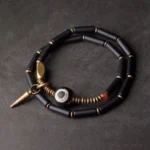 Black onyx Dzi bead double wrap Buddhist protection bracelet with antique copper cone pendant, top-down flat lay view
