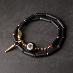 Black onyx Dzi bead double wrap Buddhist protection bracelet with antique copper cone pendant, top-down flat lay view