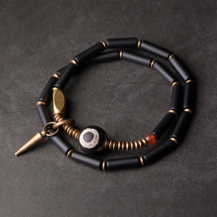 Black onyx Dzi bead double wrap Buddhist protection bracelet with antique copper cone pendant, top-down flat lay view