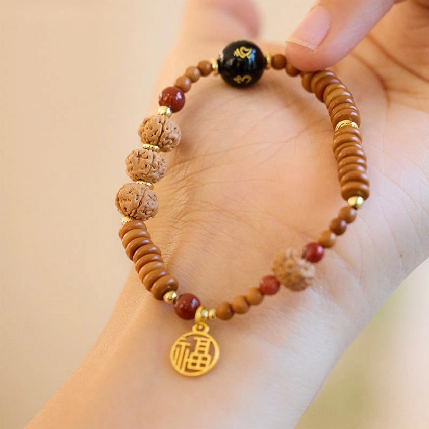 Close-up view of engraved black onyx bead and gold Fu character charm on Bodhi seed prosperity bracelet