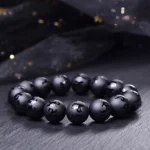 Black onyx Om Mani Padme Hum carved protection bracelet with engraved Sanskrit mantras, flat lay shot showing round matte black beads with mantra text