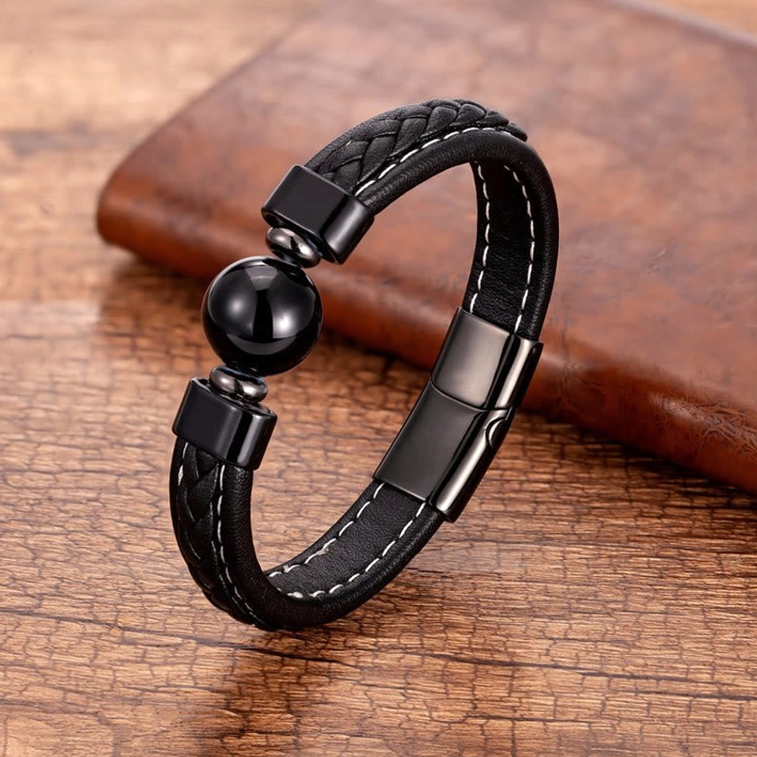 Black Onyx Om Mani Padme Hum leather bracelet with polished black stone bead on wooden surface, showing braided leather construction