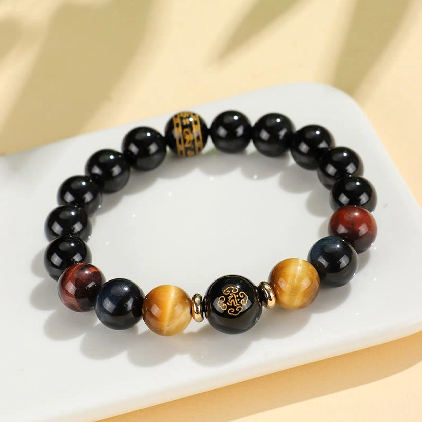 Black onyx tiger eye zodiac natal Buddha bracelet arranged on white ceramic tray, overhead flat lay