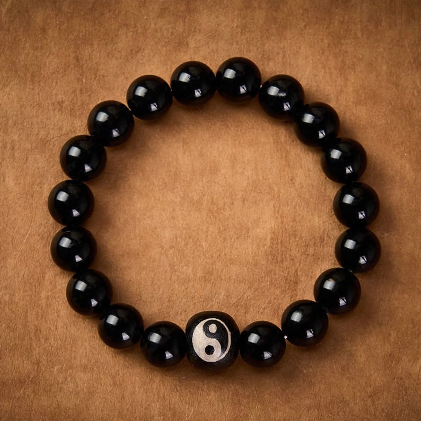Handmade black onyx yin yang protection bracelet flat lay overhead on leather background