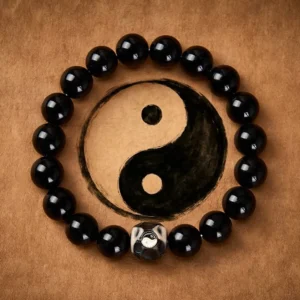 Black Onyx Yin Yang balance bracelet with engraved centerpiece on brown leather background, showing polished round beads and sacred symbol