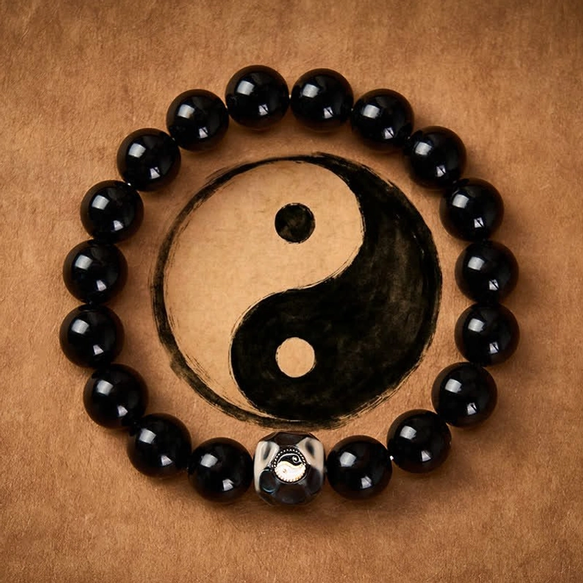 Black Onyx Yin Yang balance bracelet with engraved centerpiece on brown leather background, showing polished round beads and sacred symbol