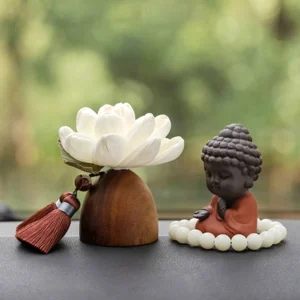 Black peach wood meditation Buddha figurine with white prayer beads on wooden table, outdoor background