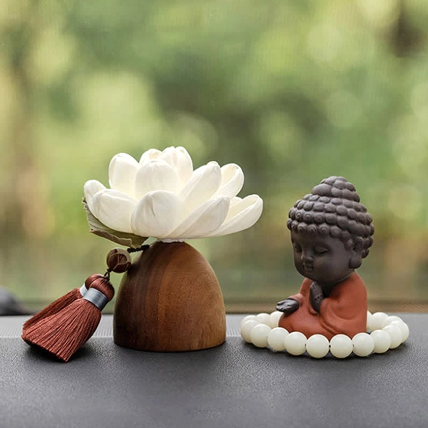 Black peach wood meditation Buddha figurine with white prayer beads on wooden table, outdoor background
