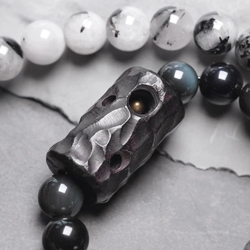 Close up of Black Rutilated Quartz bracelet with carved ebony wood pendant charm