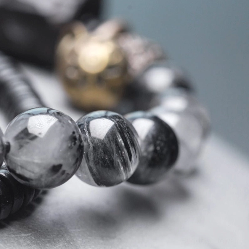 Black rutilated quartz beads with needle-like inclusions and brass spacers, macro close-up photography